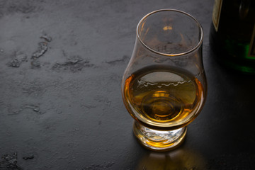 a glass of whiskey on a black background and space for text