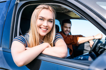 Obraz na płótnie Canvas portrait of attractive smiling woman sitting in car with boyfriend