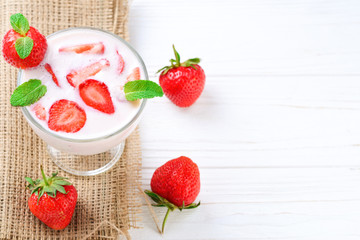 Homemade yogurt with fresh red strawberry on a wooden background. Top view.