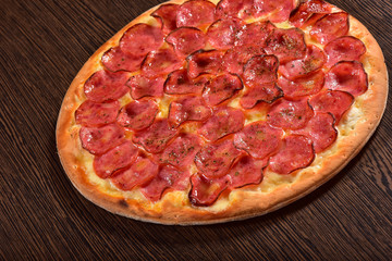 Whole pepperoni pizza on wooden background