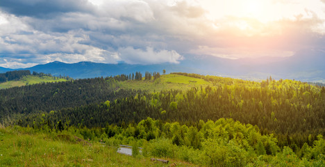 A beautiful mountain landscape - mountains, clouds, clouds, trees, and rays of the sun.