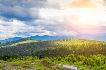 A beautiful mountain landscape - mountains, clouds, clouds, trees, and rays of the sun.