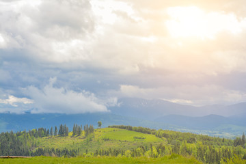 A beautiful mountain landscape - mountains, clouds, clouds, trees, and rays of the sun.
