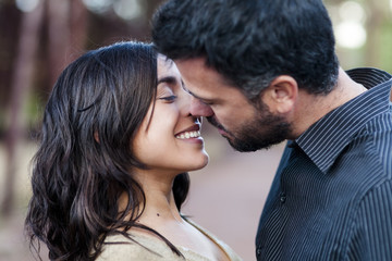 young couple in love, relaxed together in a sunny day outdoors in the forest. Young couple with dark hair closer about to kiss