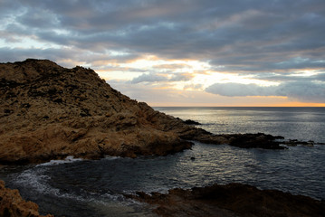 dramatic rocky shoreline with horizon and dark clouded sky beyond