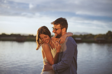 Young couple in love flirting by the river at sunset