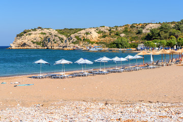 Fototapeta na wymiar Sun loungers with umbrellas on sandy Kolymbia beach. Rhodes island, Greece
