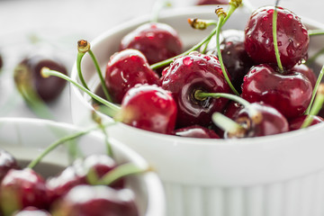 Fresh summer cherries in white bowls on grey background