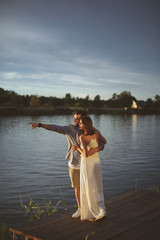 Young couple in love flirting by the river at sunset