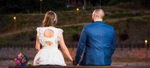 Obraz premium Bride and groom sitting by a lake at night