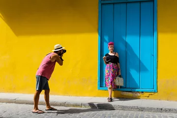 Keuken foto achterwand Havana Man die een foto maakt van een meisje tegen een gele muur
