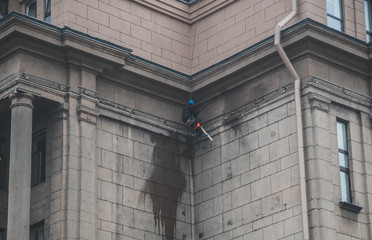 Man working with pressure washer on the wall of the building.