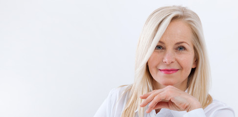 Lovely middle-aged blond woman with a beaming smile sitting at office looking at the camera