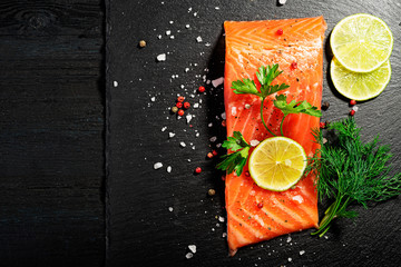 Fresh salmon fish fillet on black background, top view