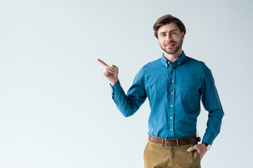 handsome young man in casual clothing pointing on blank space isolated on white