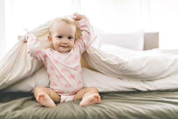 Adorable baby girl cover with white sheet wearing pink clothes
