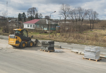 Construction of a footpath. Skid-steer loader and curbs.