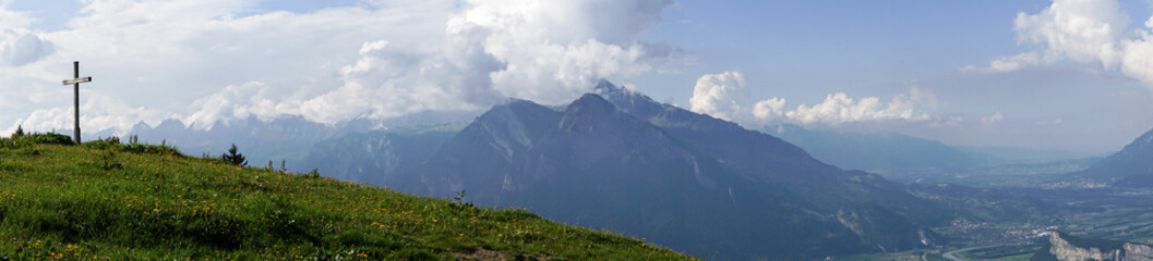 mountain panorama with a gorgeous view of the Swiss Alps and Valleys and a summit cross 