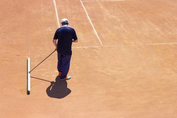 Preparation of a ground tennis court. A man is cleaning a tennis court
