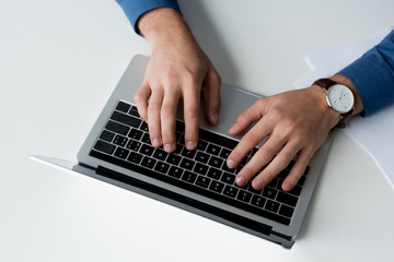 Fototapeta na wymiar cropped shot of man working with laptop on white surface