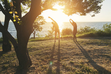  A sports couple trains together early in the morning at dawn by the sea.