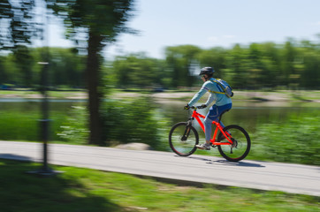 A cyclist in a helmet rides a bicycle path, motion blur