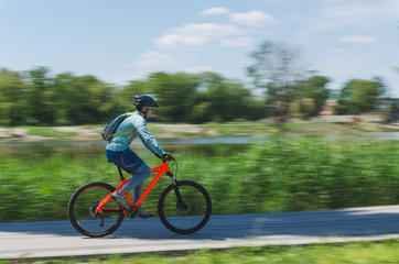 Fototapeta premium A cyclist in a helmet rides a bicycle path, motion blur