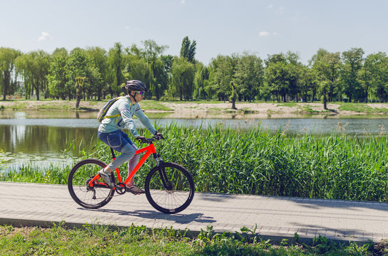 A cyclist in a helmet riding a bicycle path by the river