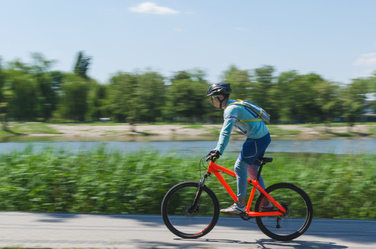 A cyclist in a helmet rides a bicycle path, motion blur