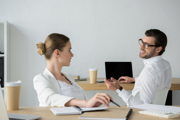 Obraz premium happy young business colleagues chatting at workplace in office