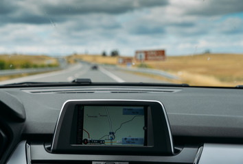 Selective focus of built in GPS navigator on dashboard of a car going down the scenic highway in...