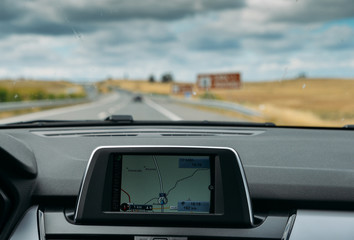 Selective focus of built in GPS navigator on dashboard of a car going down the scenic highway in Algarve, Portugal