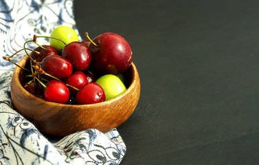 summer fruit in a wooden bowl; cherry and plum