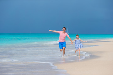 Family of father and sporty little girl having fun on the beach