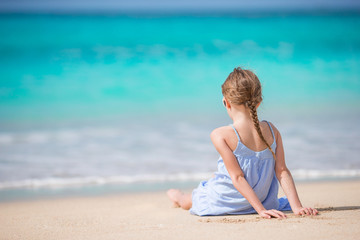 Fototapeta na wymiar Beautiful little girl in dress at beach having fun.