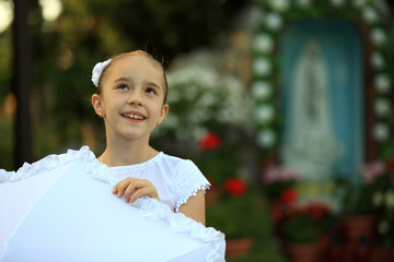 Fototapeta Śliczna mała dziewczynka w białej sukience przy chrześcijańskiej kapliczce. obraz