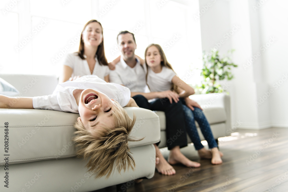 Wall mural family of four having fun on the sofa at home