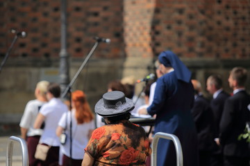 Stara kobieta w kapeluszu słucha muzyki i śpiewu chóru. - 208297207