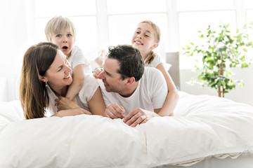 Obraz premium Family of four having fun on the bed at home