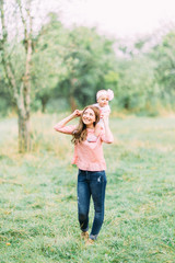 Obraz premium Mother and little daughter playing together in a park. Happy cheerful family. Mother and baby kissing, laughing and hugging in nature outdoors