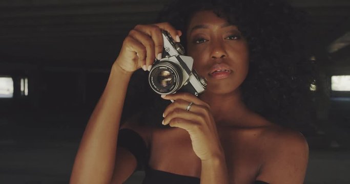 Beautiful young woman shooting photos with film camera in urban downtown setting