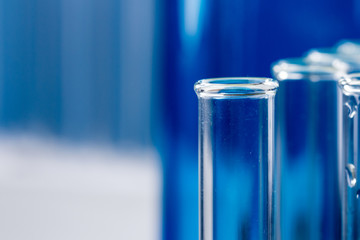 Glass test tubes on blue background in laboratory.