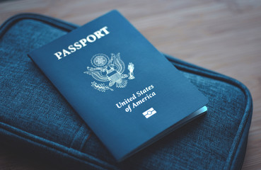 Passport of USA (United States of America) on blue travel wallet, wooden background. Close up.