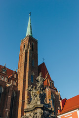 Fototapeta na wymiar bottom view of Church of Holy Cross tower with St Bartholomew statue, Wroclaw, Poland