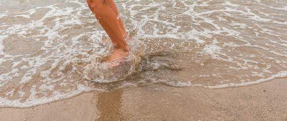 Boy's feet closeup. A boy is bouncing in the coastal water.
