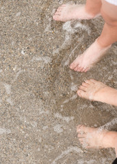 child's and woman's leg on the shore of the beach