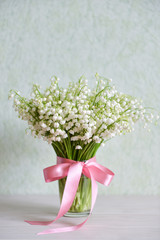 bouquet of wild lily-of-the-valley stands on the table indoors background