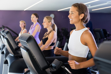 Fototapeta na wymiar Portrait of young fitness women jogging on treadmill