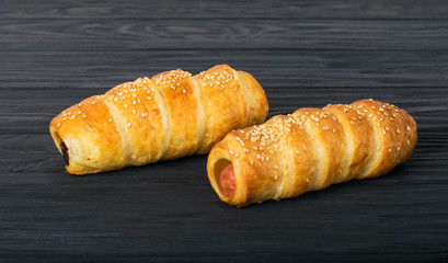 Sausages wrapped in puff pastry. Sausages in a dough on a wooden background