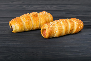 Sausages wrapped in puff pastry. Sausages in a dough on a wooden background